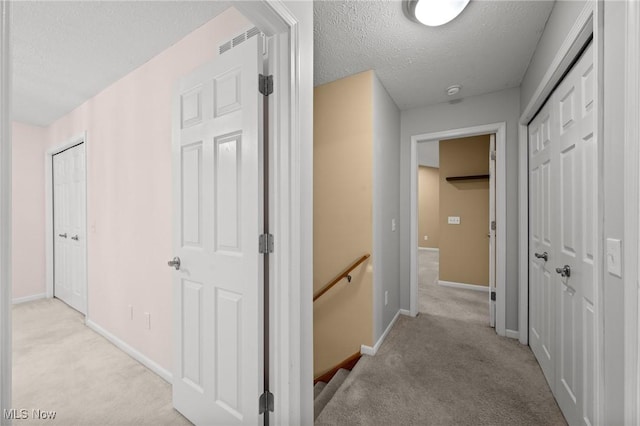 hall with a textured ceiling and light carpet