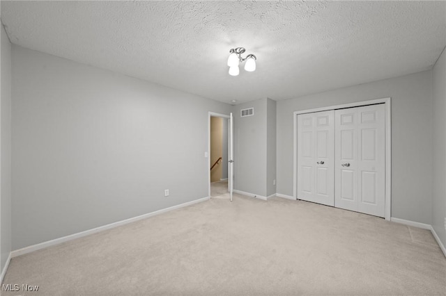 unfurnished bedroom featuring a closet, light colored carpet, and a textured ceiling