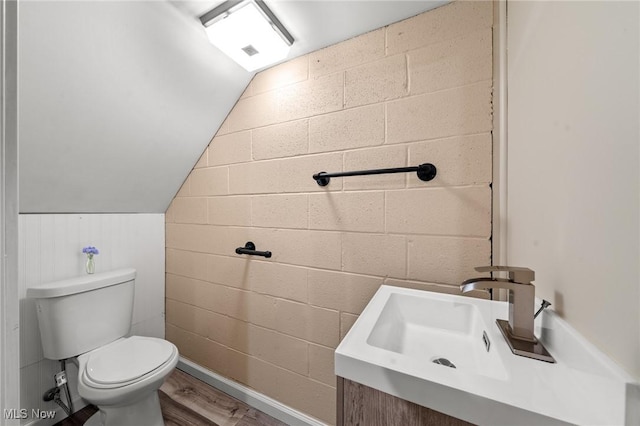 bathroom with wood-type flooring, toilet, lofted ceiling, and sink