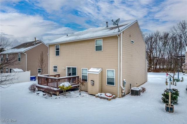 snow covered back of property with a wooden deck and central AC