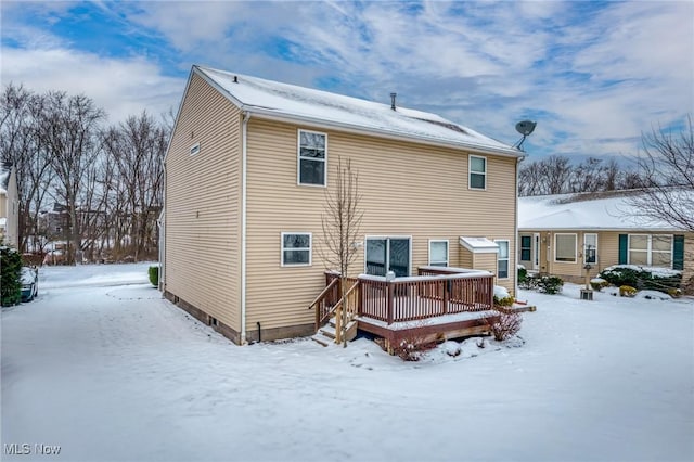 snow covered house with a wooden deck