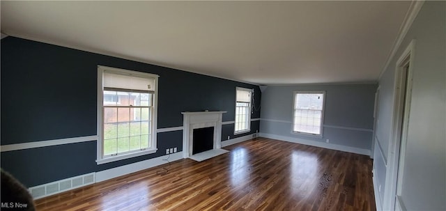 unfurnished living room with hardwood / wood-style floors, crown molding, and a healthy amount of sunlight