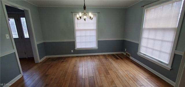 unfurnished dining area with a wealth of natural light, crown molding, hardwood / wood-style flooring, and a notable chandelier