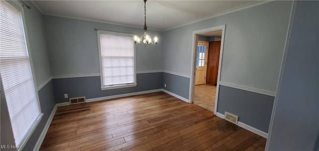 spare room featuring hardwood / wood-style floors, a notable chandelier, and crown molding