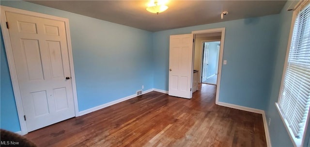 unfurnished bedroom with dark wood-type flooring