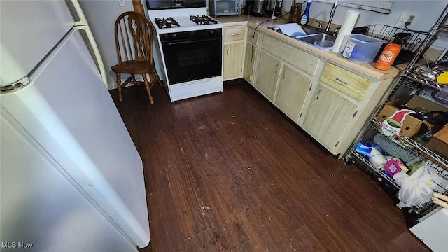 kitchen with dark hardwood / wood-style flooring, white gas range oven, refrigerator, and sink