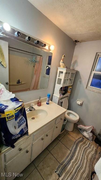 bathroom featuring a shower with shower curtain, vanity, a textured ceiling, tile patterned flooring, and toilet