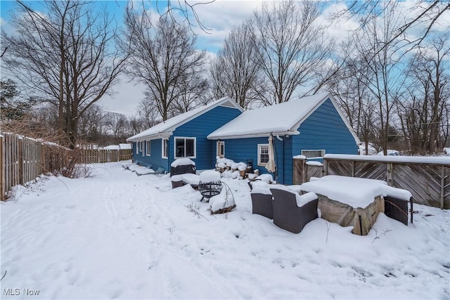 snow covered back of property with an outdoor living space