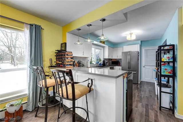 kitchen featuring stainless steel appliances, a kitchen breakfast bar, kitchen peninsula, decorative light fixtures, and white cabinets