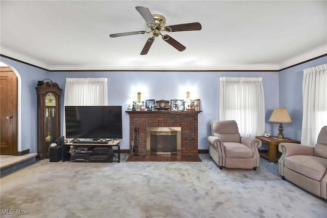 living room with carpet, ceiling fan, a wealth of natural light, and a brick fireplace