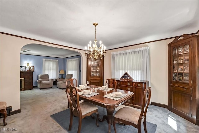 dining area featuring a fireplace, light carpet, plenty of natural light, and a notable chandelier