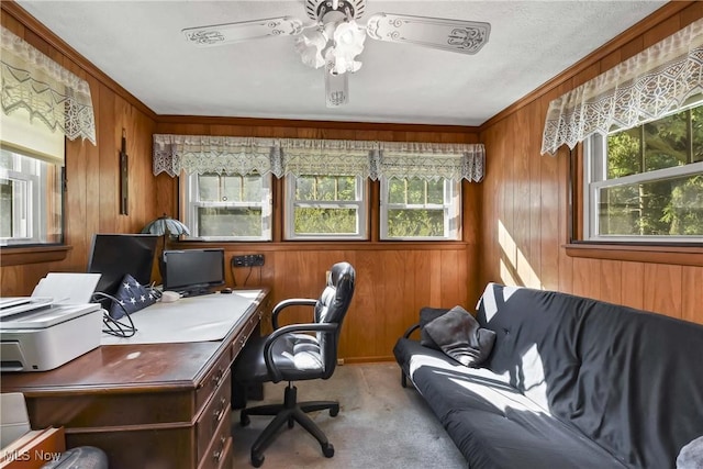 office space with light carpet, ceiling fan, and wood walls