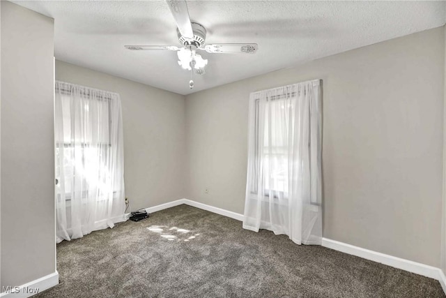 unfurnished room with a healthy amount of sunlight, ceiling fan, dark carpet, and a textured ceiling