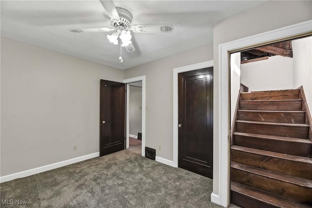 unfurnished bedroom with ceiling fan, a closet, and dark carpet