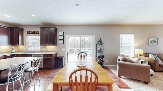 kitchen featuring a kitchen breakfast bar, sink, stainless steel dishwasher, a textured ceiling, and dark brown cabinets