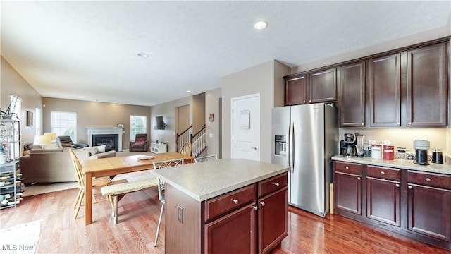 kitchen with stainless steel refrigerator with ice dispenser, a kitchen island, and hardwood / wood-style floors