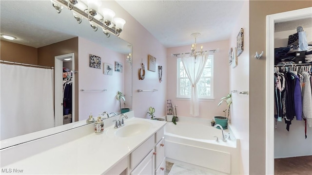 bathroom featuring a tub to relax in, vanity, a textured ceiling, and a notable chandelier