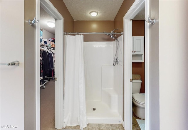 bathroom with toilet, a textured ceiling, and walk in shower