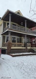 view of snowy exterior featuring a balcony and covered porch