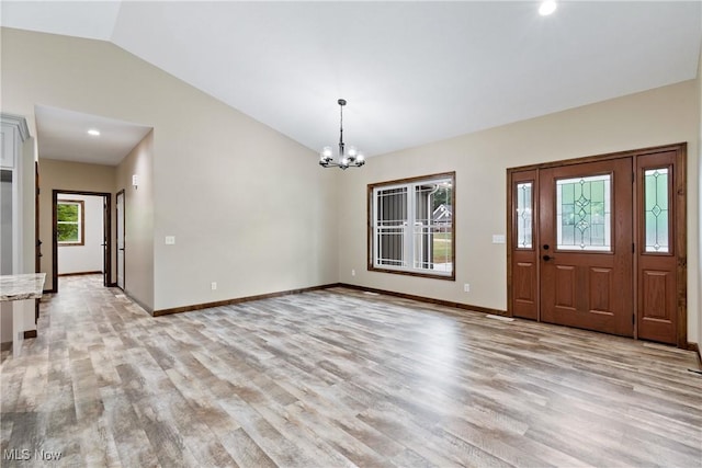 foyer entrance with light hardwood / wood-style floors, lofted ceiling, and a notable chandelier