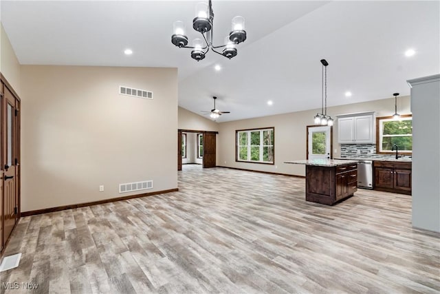 kitchen featuring tasteful backsplash, ceiling fan with notable chandelier, vaulted ceiling, dishwasher, and a center island