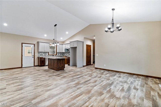 kitchen with backsplash, gray cabinets, a center island, and hanging light fixtures