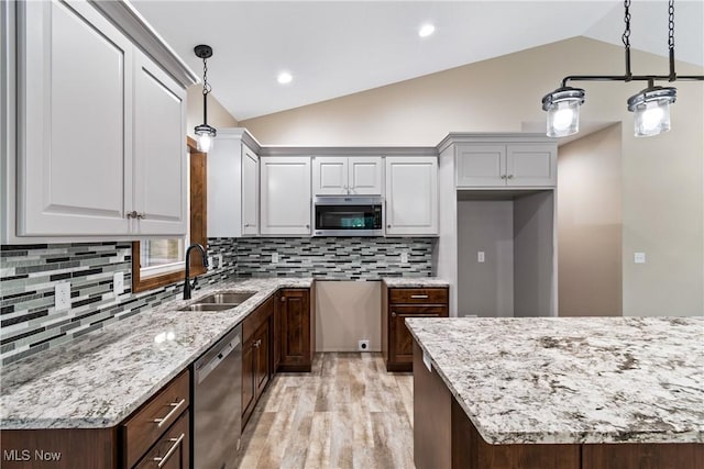 kitchen with pendant lighting, sink, stainless steel appliances, and lofted ceiling