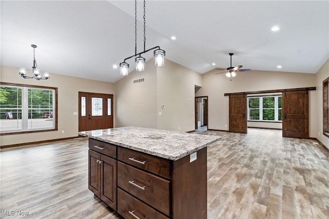 kitchen with a center island, ceiling fan with notable chandelier, a healthy amount of sunlight, and lofted ceiling