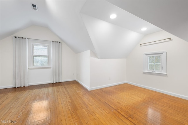 additional living space with vaulted ceiling and light hardwood / wood-style flooring