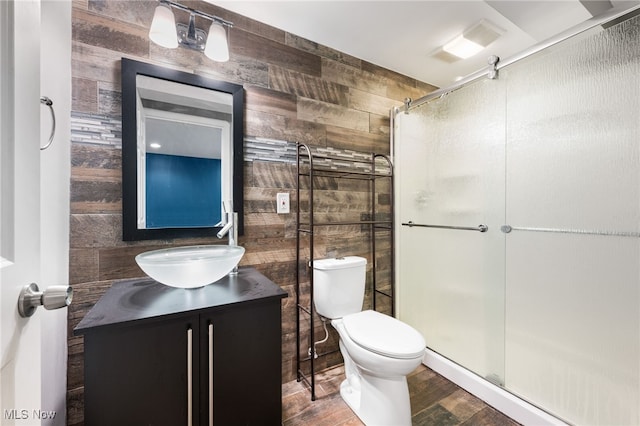 bathroom featuring hardwood / wood-style flooring, vanity, wood walls, and a shower with door