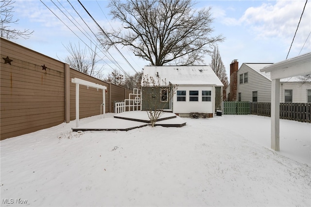 snow covered rear of property featuring an outdoor structure