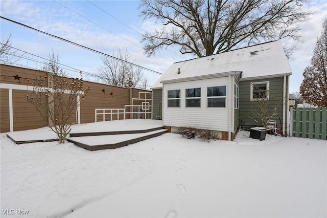 snow covered rear of property with a deck