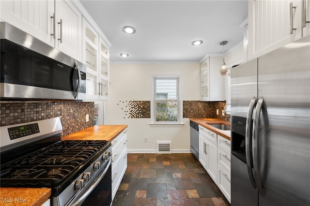 kitchen featuring pendant lighting, crown molding, sink, white cabinetry, and stainless steel appliances