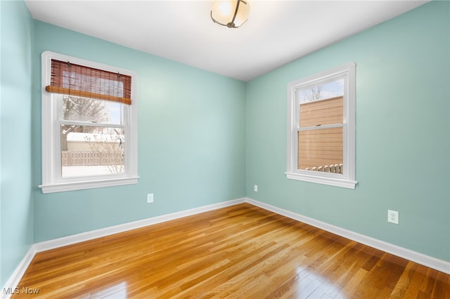 empty room with hardwood / wood-style floors and a healthy amount of sunlight