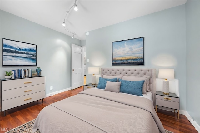 bedroom with hardwood / wood-style flooring and track lighting