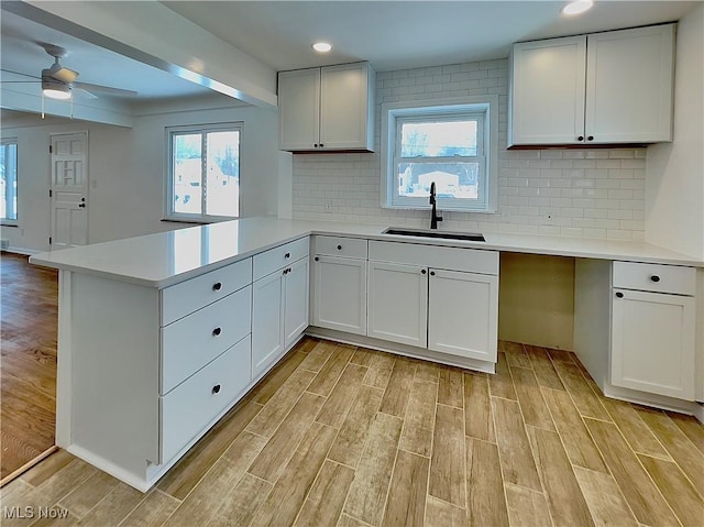 kitchen featuring white cabinets, kitchen peninsula, and sink