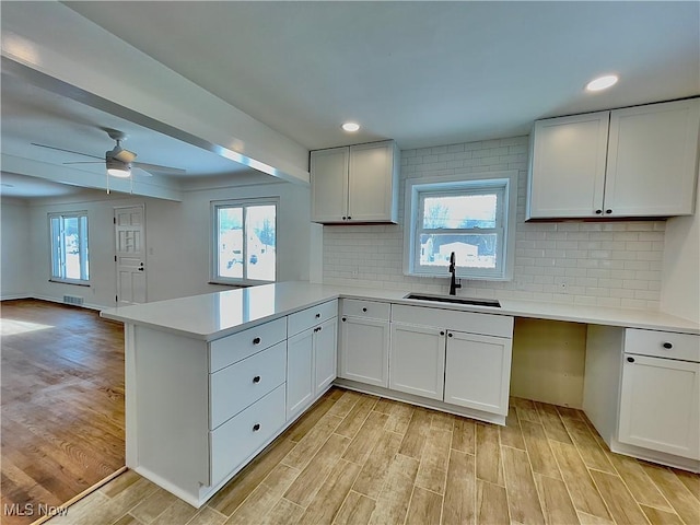 kitchen featuring white cabinetry, kitchen peninsula, ceiling fan, and sink