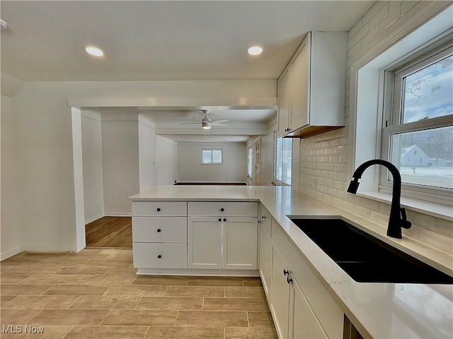 kitchen featuring white cabinets, decorative backsplash, ceiling fan, and sink