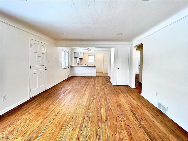 unfurnished living room featuring ceiling fan, sink, and light hardwood / wood-style floors