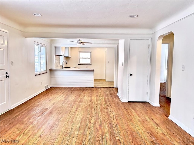 unfurnished living room featuring ceiling fan, light hardwood / wood-style flooring, and sink