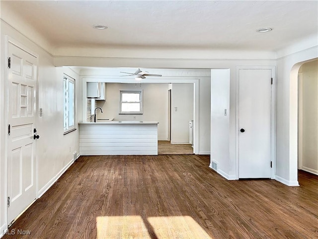 unfurnished living room with dark hardwood / wood-style floors, ceiling fan, and sink