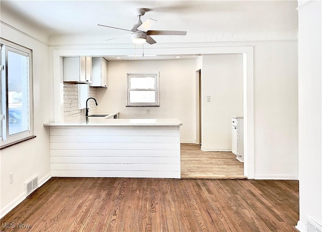 kitchen featuring kitchen peninsula, ceiling fan, sink, and dark hardwood / wood-style floors