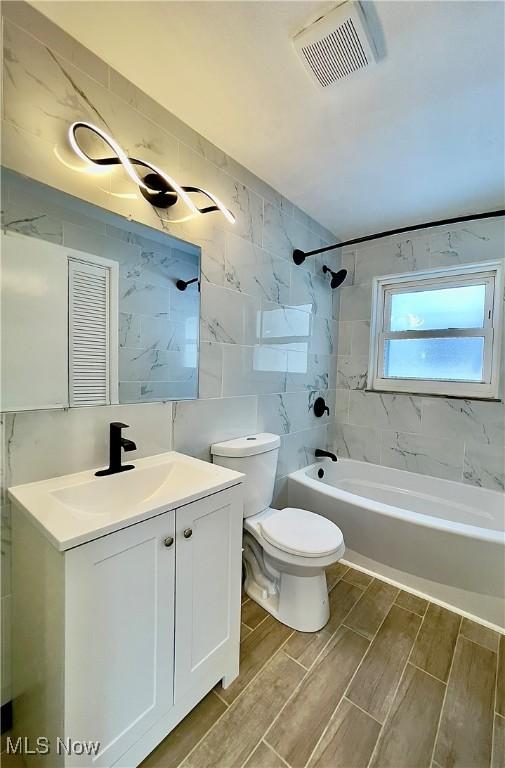 full bathroom with vanity, tiled shower / bath combo, and toilet