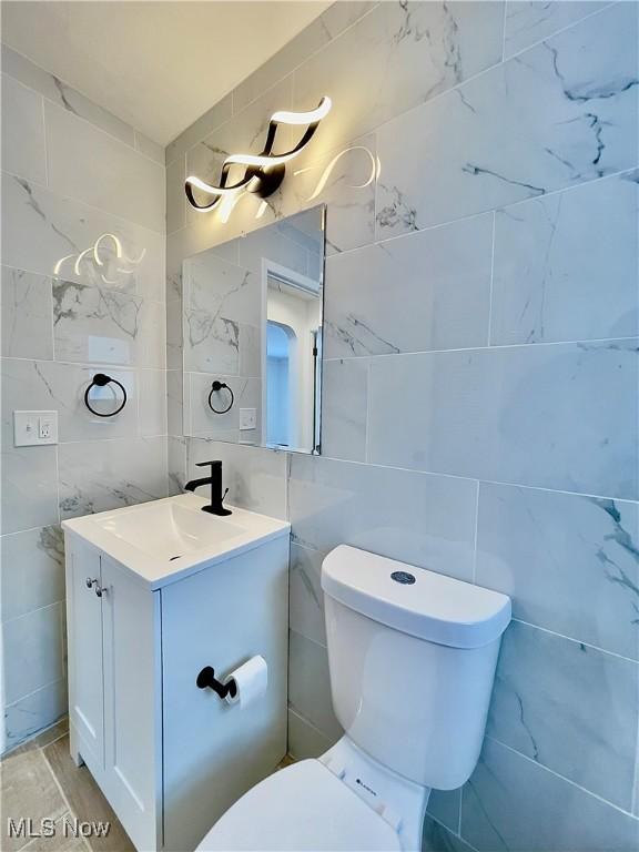 bathroom featuring hardwood / wood-style floors, vanity, tile walls, and toilet