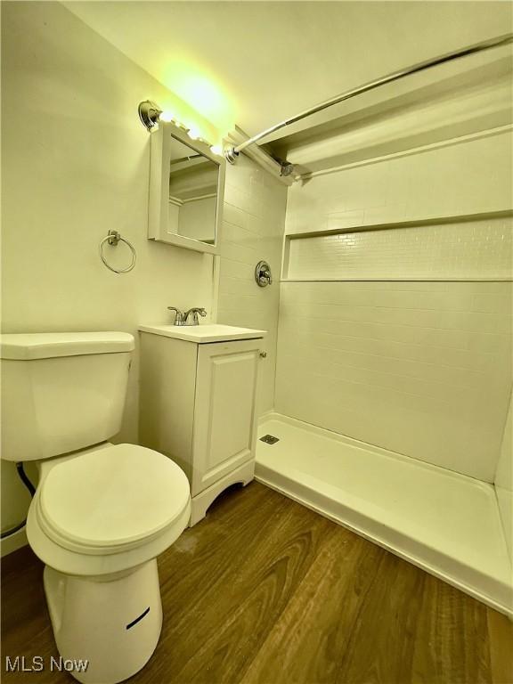 bathroom with a shower, hardwood / wood-style floors, vanity, and toilet