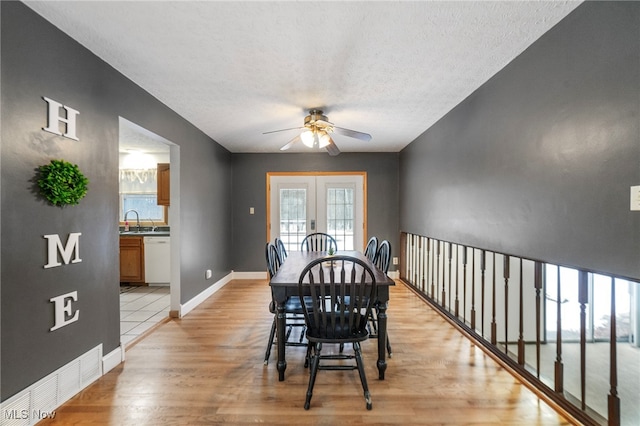 dining room with french doors, light wood-type flooring, a textured ceiling, ceiling fan, and sink