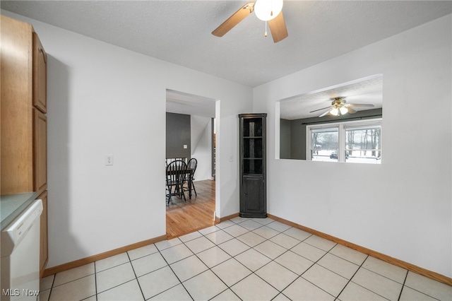 empty room featuring a textured ceiling, ceiling fan, and light tile patterned flooring