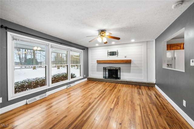 unfurnished living room with ceiling fan, light hardwood / wood-style floors, and a textured ceiling