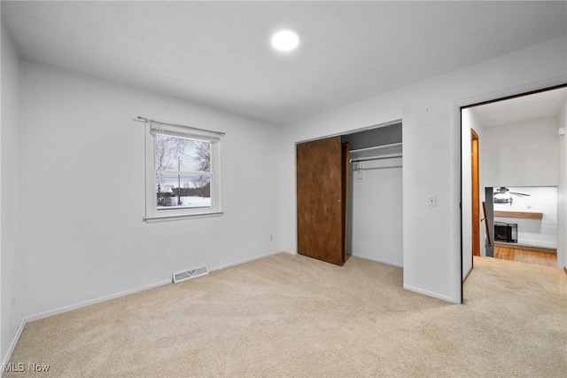 unfurnished bedroom featuring light colored carpet and a closet