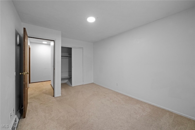 unfurnished bedroom with light carpet and a closet